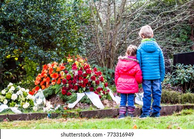 Little brother and sister standing at the grave of their parents in the graveyard