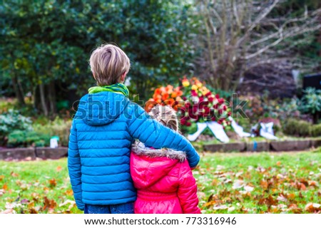 Little brother and sister standing at the grave of their parents in the graveyard