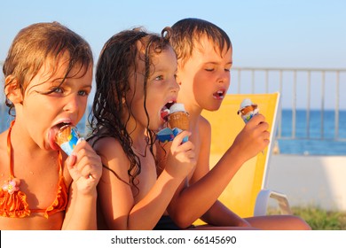 little brother and two sisters in swimsuits on beach eating ice cream after bath. focus on girl in middle