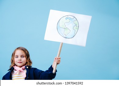 Little brunette girl holding planet earth sign in protest against pollution and waste crisis. Recycling and ecology.