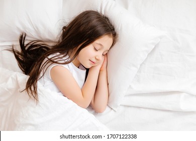 Little brunette girl sleeps sweetly in bed with white linen. space for text. healthy baby's sleep - Powered by Shutterstock