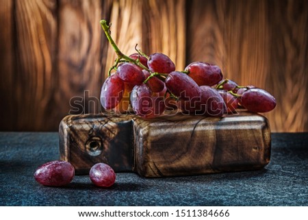 little bunch of rose grape on small vintage carving board and wooden background