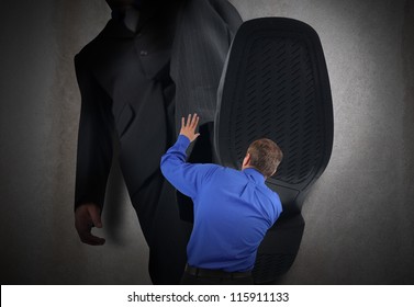 A Little Business Man Is Under A Big Bosses Foot About To Crush Or Step On Him. His Hands Are In The Air Scared.