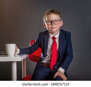 Little Businessman In The Office. Child In Suit, Red Necktie And Glasses. Fashion Kid In Elegant Suit Studying In Business School.