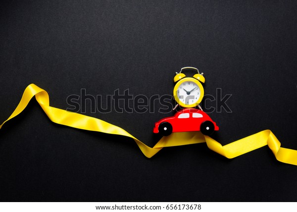 Little car with alarm clock and ribbon on\
black background