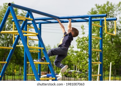 A little caucasian athletic boy climbs on the horizontal bars on the playground. A sporty child does exercises on the monkey bars in kindergarten. Children's sports and activities. Healthy lifestyle - Powered by Shutterstock