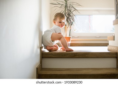 Little Caucasian Baby Is Crawling On Stairs At Home In Sunny Interior. Child Safety At Home.