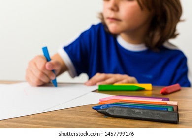 Little caucasian boy drawing with paints on his desk