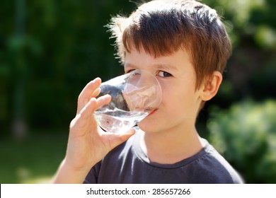 Little Caucasian Boy Drink Water In Nature