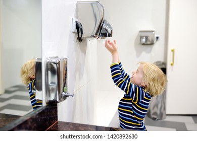 Little caucasian boy drying his hands in a restroom. Hygiene for child. - Powered by Shutterstock