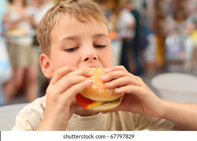 little caucasian boy eating burger, looking down