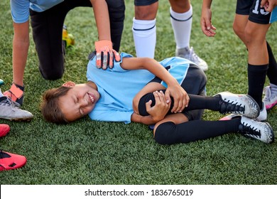 Little Caucasian Boy Fell To His Knee, Ache In Joints During Football Game Outdoors, Injury During Sport Competition