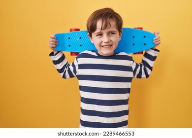 Little caucasian boy holding skate over yellow background celebrating crazy and amazed for success with open eyes screaming excited. 