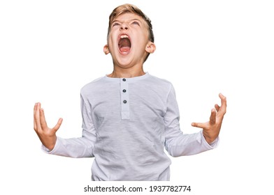 Little caucasian boy kid wearing casual clothes crazy and mad shouting and yelling with aggressive expression and arms raised. frustration concept. 