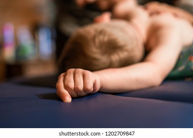 little caucasian boy lying on stomach during physiotherapy. Hand in focus