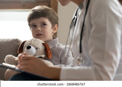 Little Caucasian Boy Patient Hug Teddy Bear Talk With Doctor Or Nurse At Consultation In Hospital. Small Child With Fluffy Toy Speak With Female GP Or Pediatrician At Regular Checkup Visit In Clinic.