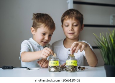 little caucasian boys putting coin into glass bottle at the table. Kid saving money for education and toys. Image with selective focus and grain effect