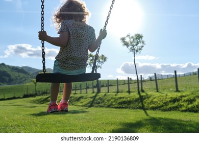 Little Caucasian Girl Alone And Sad On The Swing In The Park - Playground- Concept Of Shyness, Autism, Social Problems