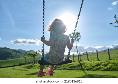 Little Caucasian Girl Alone And Sad On The Swing In The Park - Playground- Concept Of Shyness, Autism, Social Problems