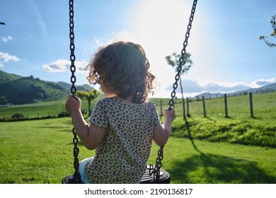 Little Caucasian Girl Alone And Sad On The Swing In The Park - Playground- Concept Of Shyness, Autism, Social Problems