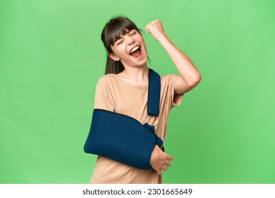 Little caucasian girl with broken arm and wearing a sling over isolated background celebrating a victory
