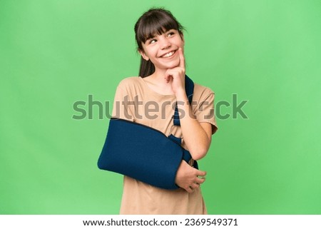 Little caucasian girl with broken arm and wearing a sling over isolated background thinking an idea while looking up