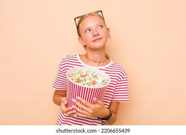 Little Caucasian Girl Eating Popcorn Isolated On Beige Background