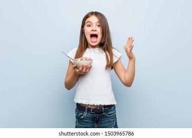 Little Caucasian Girl Holding A Cereal Bowl Celebrating A Victory Or Success