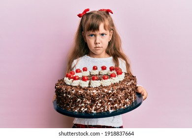 Little Caucasian Girl Kid Celebrating Birthday Holding Big Chocolate Cake Skeptic And Nervous, Frowning Upset Because Of Problem. Negative Person. 