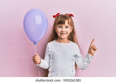 Little Caucasian Girl Kid Holding Purple Balloon Smiling Happy Pointing With Hand And Finger To The Side 