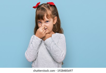 Little Caucasian Girl Kid Wearing Casual Clothes Smelling Something Stinky And Disgusting, Intolerable Smell, Holding Breath With Fingers On Nose. Bad Smell 