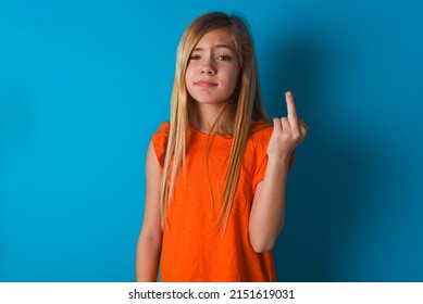 Little Caucasian Kid Girl Wearing Orange T-shirt Over Blue Background Shows Middle Finger Bad Sign Asks Not To Bother. Provocation And Rude Attitude.