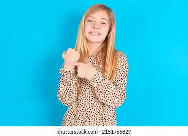 Little Caucasian Kid Girl Wearing Animal Print Sweater Over Blue Background In Hurry Pointing To Wrist Watch, Impatience, Looking At The Camera With Relaxed Expression