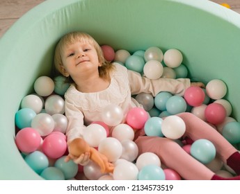 A Little Cheerful Girl Lies In Colorful Balloons In A Dry Pool. Top View