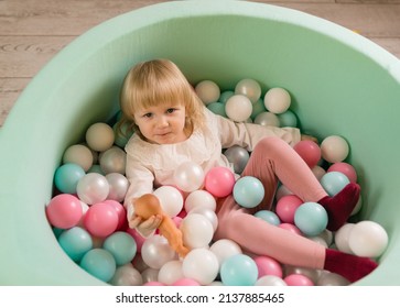 A Little Cheerful Girl Is Playing With Colorful Balloons And A Doll In A Dry Pool. Top View