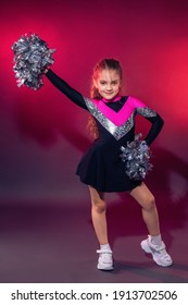 Little cheerleader practicing dance elements in studio with color light