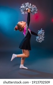 Little cheerleader practicing dance elements in studio with color light