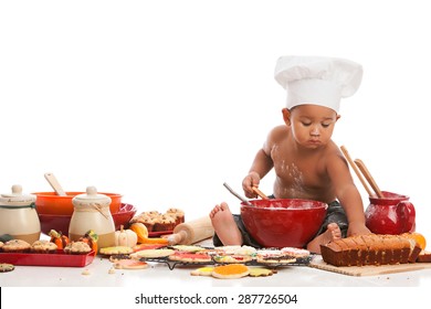 Little Chef.  Adorable biracial baby wearing a chef's hat and surrounded by baked goods.  Isolated on white with room for your text.