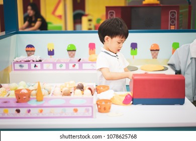 A little chef is playing a ice-cream toy at the playground.