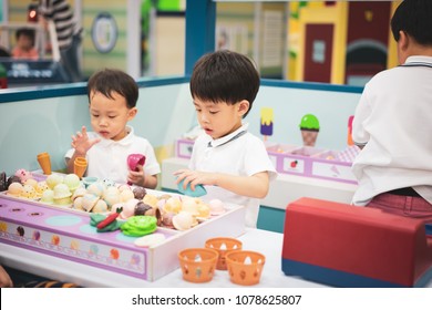 A little chef is playing a ice-cream toy at the playground.