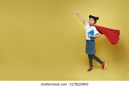 Little child asian girl superhero holding book on yellow background. Girl power hero concept. - Powered by Shutterstock