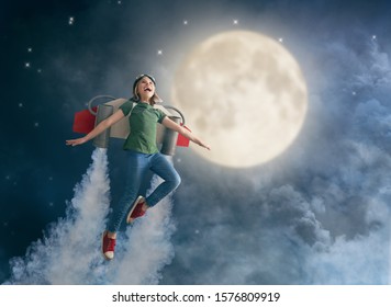 Little child in an astronaut costume is playing and dreaming of becoming a spaceman. Portrait of funny kid on a background of night sky.                               