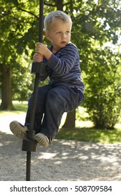 Little Child Blond Boy Climbing Rope On The Playground Outdoors
