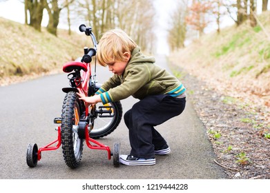 Little Child Boy On Bicycle In Park Outdoor. A Child Is Riding A Children's Bike With Training Support Wheels 