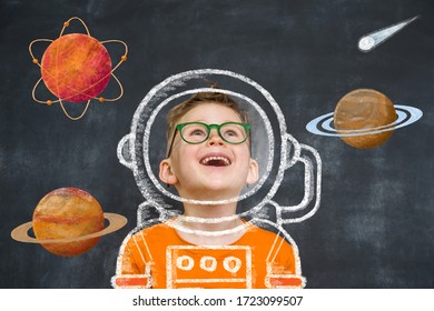 Little Child Boy Play Astronaut In Space Suit And Drawn Planets Around.  Orange Uniform And Green Glasses Against Black