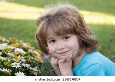 Little Child Boy Is Smelling Flowers On Green Backyard. Adorable Kid On A Summer Meadow And Smelling Flowers. Summer Fun For Family With Kids Outdoors In A Beautiful Spring Garden.
