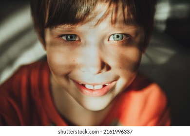 Little Child Boy Smiling With Sunny Rays On Face. Cute Child With Blue Eyes Smiling. Vintage Lens Kids Home Portrait In Daylight. Growing Up Psychology Personal Development