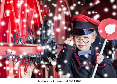 Little Child Boy In Winter As Nostalgic Railroad Conductor Beside Large Wheels Of A Steam Locomotive With Snowflakes And Text Message/Smiling Train Conductor Boy In Winter - Bon Voyage