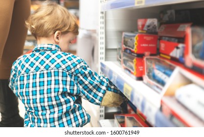 A Little Child Chooses A Toy Car In The Store