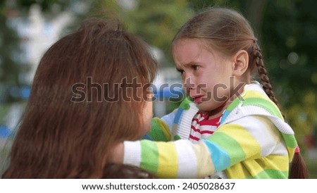 little child cries, tears child face, mother calms capricious kid girl daughter, happy family, wipe tears face, hug kid park, trying explain feelings, scared, wet drops tears face little girl daughter
